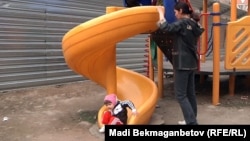 Ақсай-4 ықшам ауданының тұрғындары дуал сыртына ысырылған сырғанақта балаларын ойнатып жүр. Алматы, 7 сәуір 2012 жыл.