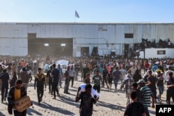 Разселени палестинци пренасят чували с хранителни помощи след щурм на склад на Световната продоволствена програма в Дейр ел-Бала в централната част на Ивицата Газа на 28 май 2025 г.