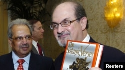 سلمان رشدی در سال ۱۹۸۸ و در حالی که یک نسخه از کتاب «آیات شیطانی» را در دست دارد.