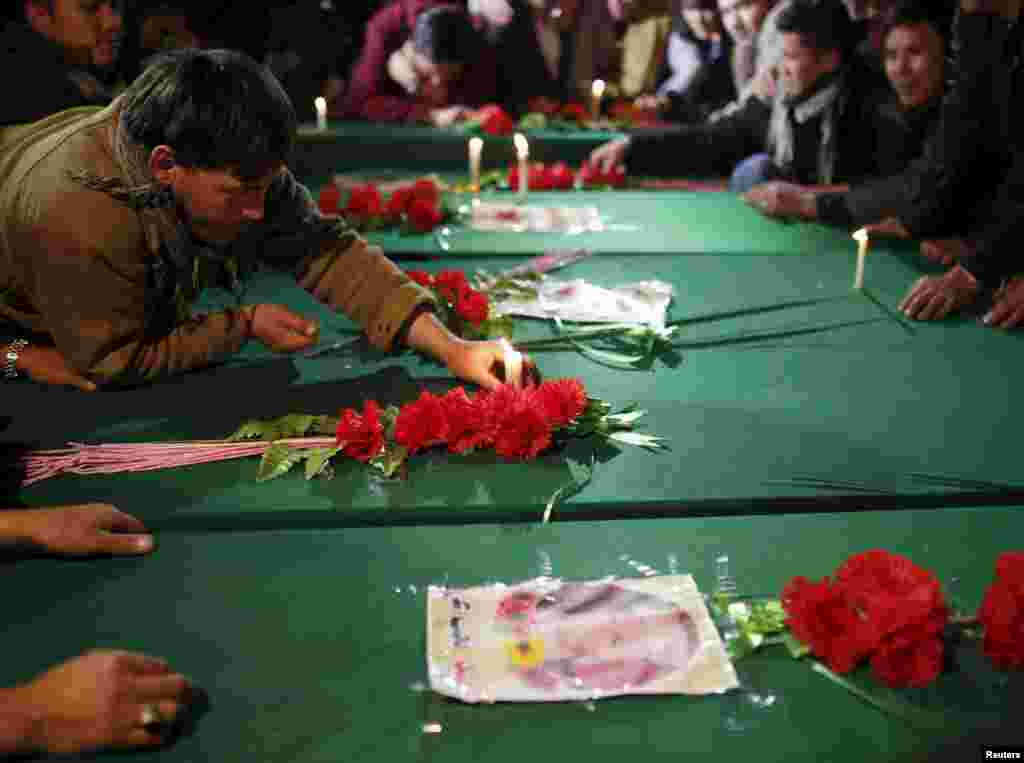 A man places a candle on top of one of the seven coffins during a procession in Kabul on November 10.