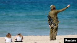 یک سرباز اسرائیلی در ساحلی در نزدیکی اشکلون در جنوب اسرائیل که پس از آتش‌بس بازگشایی شده است، ۲۴ مهر
