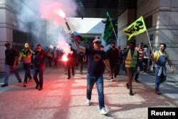 Френски железопътни работници държат червени факли, докато влизат в Министерството на икономиката и финансите в Париж.