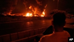 Мужчына назірае за полымем над нафтасховішчам пасьля меркаванага ізраільскага авіяўдару ў Тэгеране 16 чэрвеня