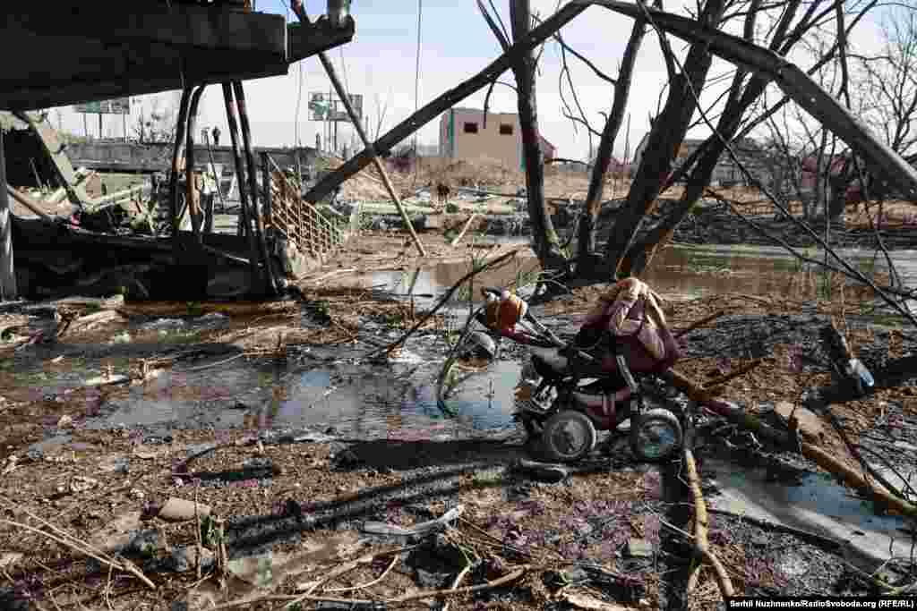 Кінуты дзіцячы вазок празь пераход каля разбуранага Раманаўскага мосту.Зьлева фота 11 сакавіка 2022 году, справа — з сакавіка 2025 году