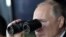 Ресей президенті Владимир Путин әскери жаттығу кезінде бинокльмен төңіректі шолып отыр. 