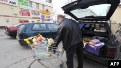 Мужчына загружае машыну таварамі, набытымі ў польскім супэрмаркеце