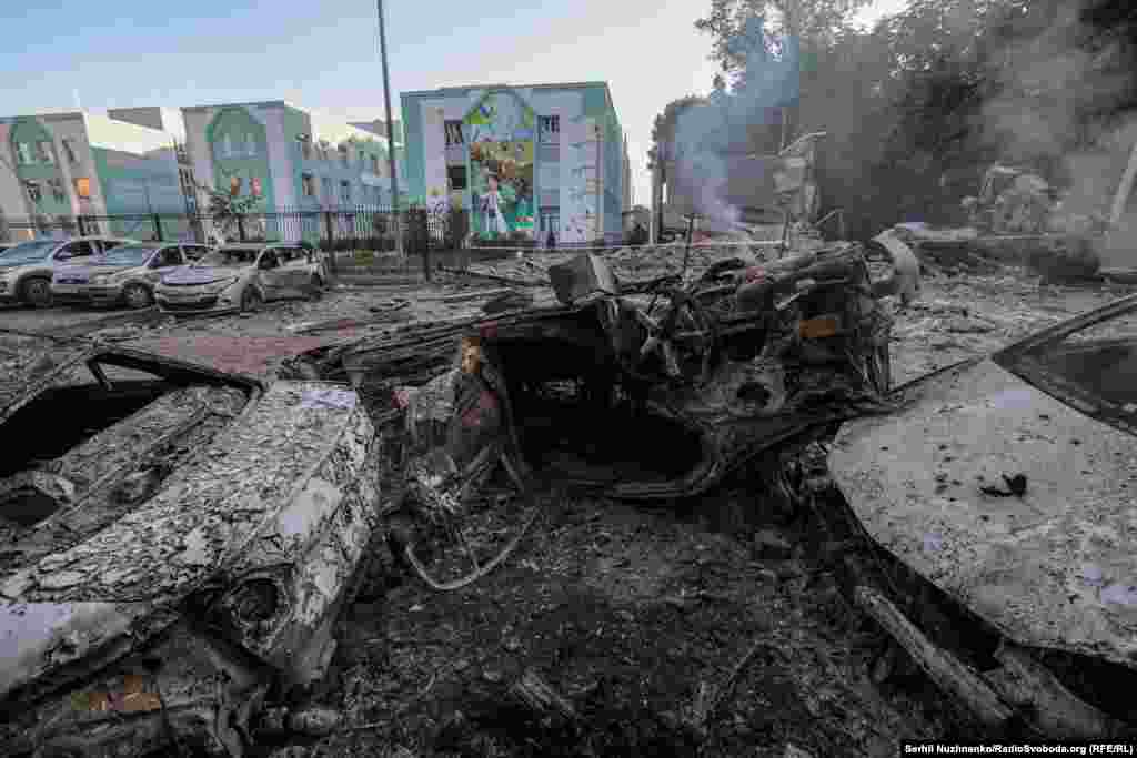 Пошкоджений російським обстрілом освітній заклад у одному з районів Києва. Поруч знищені вогнем вщент автомобілі