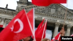 روز گذشته و با شدت گرفتن اعتراضات ترکیه به رای‌گیری، تعداد از ترک‌های ساکن آلمان مقابل ساختمان پارلمان در برلین تجمع کرده بودند