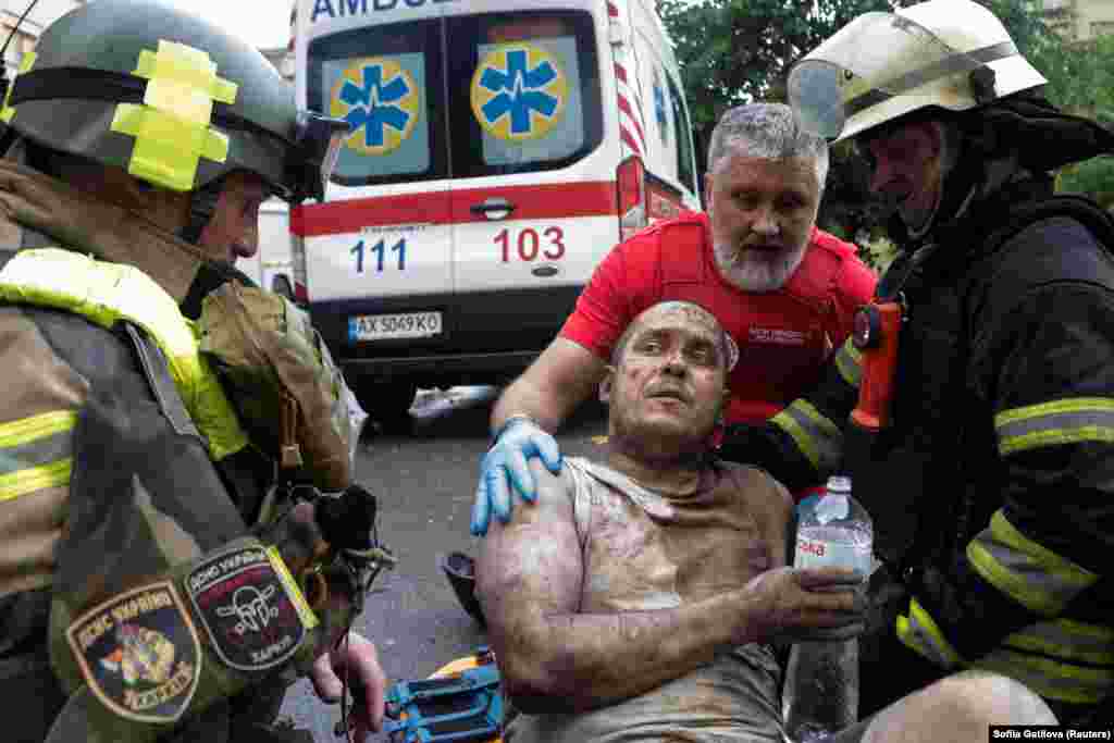 Рятувальники та парамедик розмовляють з пораненим чоловіком, якого витягли з-під завалів будівлі, що постраждала внаслідок удару російського безпілотника на тлі нападу Росії на Україну, Харків, 7 червня 2025 року