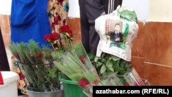 Türkmenistanda gül desseleriniň biriniň daşyna dolanan gazetde öňki prezident, häzir Halk Maslahatynyň başlygy Gurbanguly Berdimuhamedowyň suratyny görse bolýar. (Arhiw suraty)