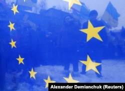 Крізь прапор ЄС проглядаються протестувальники під час Євромайдану у Києві, який переріс у Революцію Гідності. Київ, 17 грудня 2013 року