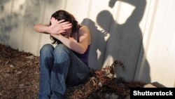 Женщина закрывает лицо от ударов. Иллюстративное фото.