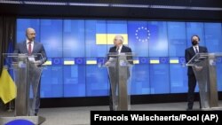 Украин премьери Денис Шмыгал (солдо), ЕБнын тышкы саясат боюнча башчысы Жосеп Боррел,  ЕБнын коңшулук жана кеңейтүү боюнча комиссары Оливер Вархели. Брүсселдеги маалымат жыйыны. 2021-жылдын 11-февралы.