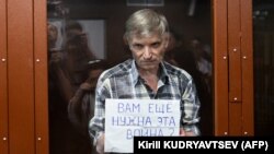 Moscow city deputy Aleksei Gorinov, who is accused of "distributing false information" about Russia's war in Ukraine, holds up a sign reading, "Do you need this war?" at his verdict hearing at a courthouse in Moscow on July 8.