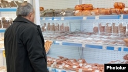 Armenia -- A man looks at meat products at a food store in Yerevan.