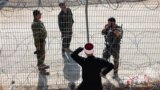 Сирийский друз разговаривает с израильскими солдатами через решетку и колючую проволоку на линии размежевания на Голанских высотах. Мадждаль-Шамс, 17 июля 2025 года