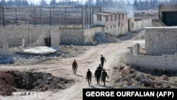 چند سرباز هوادار اسد در حال گشت‌زنی در ویرانه‌هایی در منطقه مساکن هنانو، تنها سه روز پیش از اعلام باز‌پس‌گیری کامل این منطقه توسط نیروهای دولتی