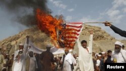 Әфганстанда бер төркем протест белдерүче американ әләмен яндыра