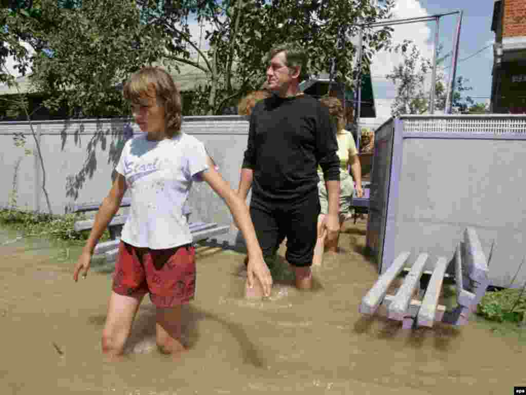 epa01425033 President of Ukraine Viktor Yushchenko (C) leaves a flood victims home during his visit to Poberezhya village of Ivano-Frankivsk region, Western Ukraine, 27 July 2008. At least 16 people have died in severe storms and flooding in western Ukraine and northern Romania which forced thousands to abandon their homes, authorities said on 27 July. EPA/MYKHAYLO MARKIV/ POOL
