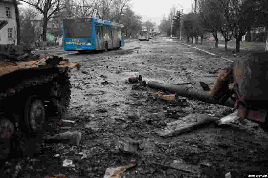 Uglegorsk township, Donetsk region, Ukrain. The territory is under DNR (rebels) control. The line of buses passes by burnt ukrainian tank.