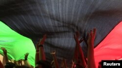 Ливиялыктар тобу Эл аралык кылмыш соту тарабынан Муаммар Каддафини камакка алуу тууралуу буйрук чыгарылганын угуп, шаттанууда. Бенгази ш., 2011-жылдын 27-июну.