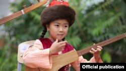 Музыкалык мектептин ачылыш салтанатында күү черткен кыз. 