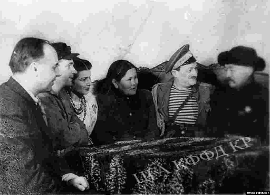 Кыргызстандан барган делегация Ленинграддын музыкалык комедия театрында. Спектаклдын антрагында артисттер делегаттар менен маектешүүдө. (Оң тарапта) төкмө акын, Кыргыз ССРинин эл артисти Алымкул Үсөнбаев, (3чү) Кыргыз ССРинин Жогорку сотунун төрайымы Фатима Кадырбаева. Ноябрь, 1943-жыл. Ленинград шаары.&nbsp;