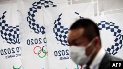 Պաշտպանիչ դիմակով լրագրողը մասնակցում է 2020 թվականի Ամառային օլիմպիադայի կազմկոմիտեի ասուլիսին, Տոկիո