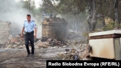 A police officer inspects burned-out houses in the village of Chelopek, North Macedonia, on August 5. 