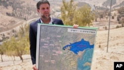 Израелският министър на финансите Бецалел Смотрич, който е сред крайнодесните представители в правителството, държи карта на проекта за нови израелски селища в Западния бряг, 14 август 2025 г.
