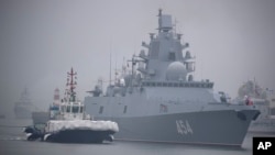 A tugboat escorts the Russian frigate Admiral Gorshkov as it prepares to dock at a port in Qingdao, China in 2019. 