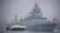 A tugboat escorts the Russian frigate Admiral Gorshkov as it prepares to dock at a port in Qingdao, China in 2019. 
