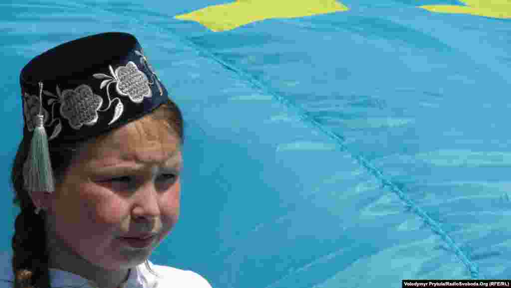 Дівчинка несла велике полотнище кримськотатарського національного прапору