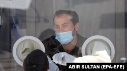 Израилдик медицина кызматкери коронавируска карата тест алып жаткан учур.