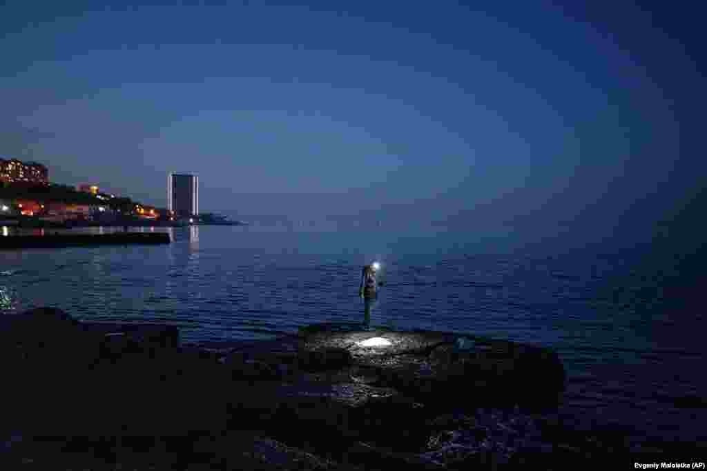 مردی در حال ماهی‌گیری روی موج‌شکن در ساحل آرکادیا در بندر اودسای اوکراین.