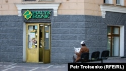 Алматыдағы Halyk bank бөлімшелерінің бірінің алдында отырған адам (көрнекі сурет)