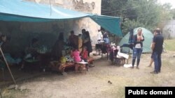 Өртенген үйдің тұрғындары шатырларының маңында отыр. Алматы, 18 тамыз 2014 жыл. Сурет Искандер Раимов атты интернет қолданушының Facebook парақшасынан алынды.  