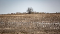 Колючий дріт вздовж лінії зіткнення між КПВВ «Золоте» та окупованим Первомайськом (у полі)