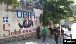 Ljudi prolaze pored zida na kojem je prikazan predsednik Haitija, Port-au-Prince na Haitiju 7. jula 2021.
