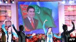 Девушки танцуют перед портретом президента Гурбангулы Бердымухамедова во время празднования исламского праздника Ид аль-Адха в Ашхабаде, 17 ноября 2010 года