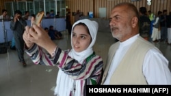 Afghan teenager Fatema Qaderyan takes a photograph with her father at Herat International Airport before heading to the United States last month for a robotics competition.