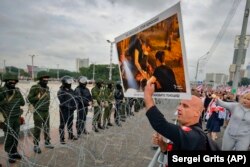 Александр Лукашенконың биліктен кетуін талап етіп бейбіт шеруге шыққан азаматтар мен олардың жолын бөгеп тұрған қарулы әскерилер. Минск, 23 тамыз 2020 жыл.