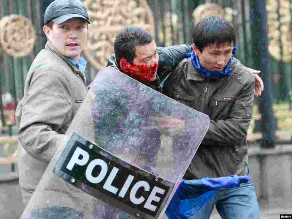 Участники протеста несут раненного в результате столкновения демонстрантов с милицией. Бишкек, 7 апреля 2010 года.