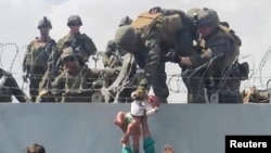 Немовля передають американським військовим через загороджувальну стіну аеропорту Кабула під час евакуації людей, які хочуть втекти від талібів. Афганістан, 19 серпня 2021 року.