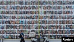 مردی در حال عبور از مقابل تصاویر گروگان‌های اسرائیلی در تل‌آویو، که توسط گروه افراطی حماس ربوده و به غزه منتقل شدند