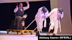 "Заңдастырылған заңсыздық" спектаклінен көрініс. Мұнай өндіруші Лангманның (актер Звиад Папуашвили) жаңадан ашылған кенішке бара жатқан сәтін бейнелеген кез. Жолбасшы ролінде - Бека Сонгулашвили, жүкші - Давид Гоциридзе.   Алматы, 23 маусым 2018 жыл 