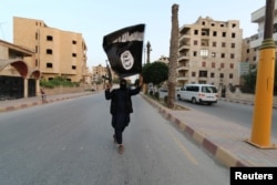 Боевик «Исламского государства» размахивает флагом ИГ в сирийском городе Ракка