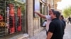 People look at currency exchange rates displayed on an electronic board on the window of a shop in in Ferdowsi Square in the Iranian capital Tehran on September 28.