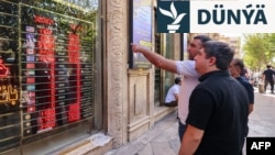 Adamlar 28-nji sentýabrda Eýranyň paýtagty Tähranyň "Ferdowsi" meýdanyndaky dükanyň penjiresinde, elektron tagtada görkezilen walýuta alyş-çalyş nyrhyna seredýärler.