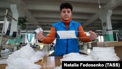Работница фабрики в Бобруйске (Могилёвская область) проверяет защитные маски, 12 марта 2020